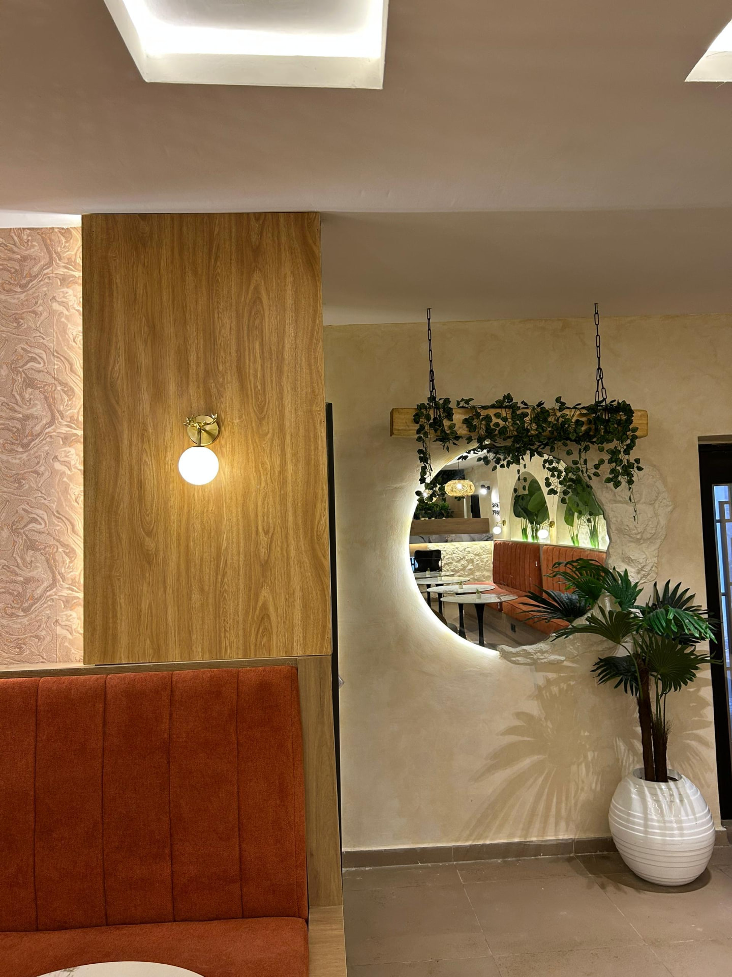 Backlit round mirror and greenery in the lounge